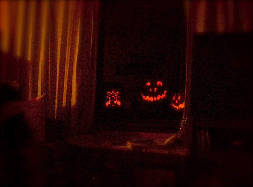 This is cool: we have the ideal setup for enjoying jack-o'-lanterns. They inhabit a table outside the window, out in the dark and the cold that they prefer; but they peer in at us with their flickering eyes, which they also love to do.