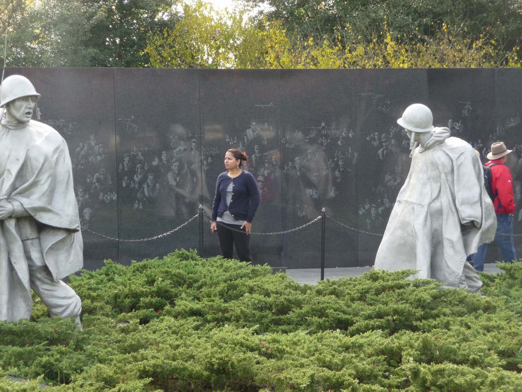 Note how the figures are reflected in the wall among the etchings of faces there, so many men and women of service, a great and silent company.